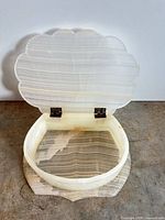 Open carved alabaster seashell trinket box showing interior banding and metal hinges