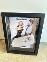 Front view of framed signed tie and Sugarland photo