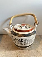 Full view of porcelain teapot showing body, spout, handle, script and decorative band