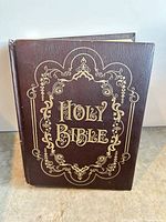 Front view of the Bible showing brown cover, gold filigree, and title