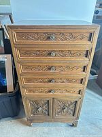 Full view of carved wood cabinet showing five drawers and lower cupboard doors