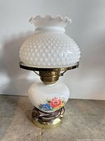 Front view showing hobnail milk glass shade, floral base and brass fittings