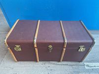 Closed burgundy trunk with wooden slats and brass latches