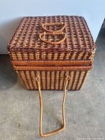 Closed square wicker basket showing top handles and carry strap