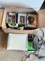 Box contents showing Xbox 360 console, controllers, cables and game lot