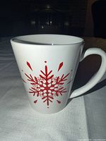 Front view of white ceramic mug with red snowflake/star design