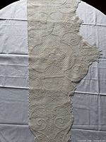 Full view of long cream lace doily on table