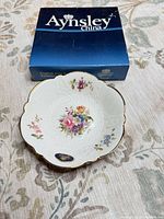 Bowl front view with box showing floral centre, scalloped gold rim