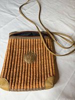 Front view of tan wicker shoulder purse with leather trim and logo patch