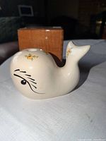 Side view of off-white ceramic whale showing painted eye and floral decal