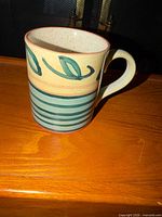Front view of ceramic mug showing leaf motif, stripes, handle