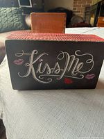 Front view of the wooden “Kiss Me” block sign