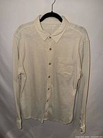 Full frontal view of cream button-down shirt on hanger