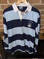 Front view of striped rugby shirt on hanger showing overall design