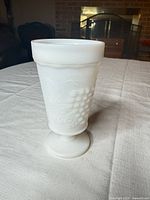 Front view of white milk glass footed tumbler showing grape pattern