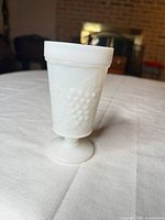 Front view of white milk glass footed tumbler showing grape cluster design