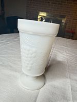 Front view of white milk glass footed tumbler showing grape cluster relief
