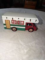 Left side view of metal camper showing faux wood door, plaid curtains and attached mini lights