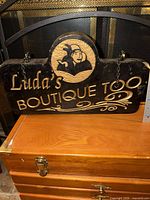 Front view of entire wooden sign showing text, logo, and hanging chains