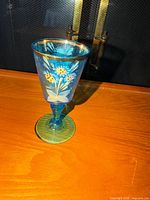 Overall view of blue glass goblet showing painted floral design