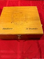 Top view of closed wooden cigar box showing crest, text Maduro 20 Piramides, brass clasp