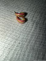 Pair of gold-tone pink enamel hoop earrings on fabric surface