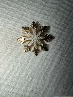 Front view of gold-tone snowflake brooch showing rhinestone detail