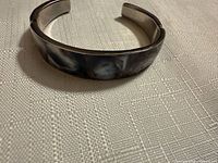 Top view of silver-tone cuff with shell/stone inlay