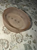 Top view of round pale pink frosted glass ashtray with four rests