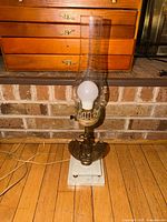 Full view of brass eagle marble base lamp with glass chimney and bulb