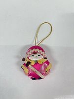 front view of closed pink doll-shaped sewing kit with gold loop
