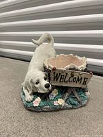 Front view of resin dog statue with planter and Welcome sign