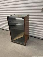 Full view of cabinet showing glass door, wood sides, casters