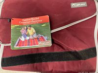 Folded red Lightspeed picnic blanket with tag visible