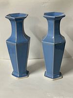 Front view of both blue faceted vases showing full shape and glaze