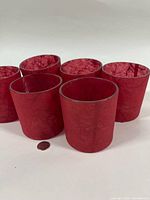 Six red paper mache votive holders beside coin for scale