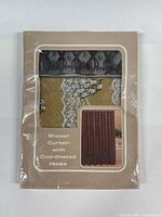 Front of sealed package showing shower curtain pattern and hooks