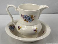 Full view of pitcher seated in basin showing overall form and matching floral design