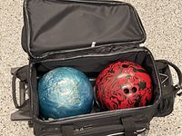 Open tote showing blue Ice and red/black Cardinal bowling balls