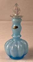 Full view of blue opalescent perfume bottle with clear stopper