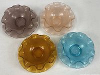 Four coloured ruffled bowls with matching plates overview