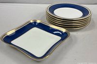 Stack of six cobalt and gold rim bowls beside square dish