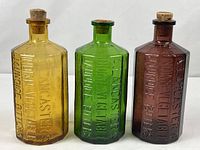 Group shot of three colored Wheaton replica bitters bottles with corks