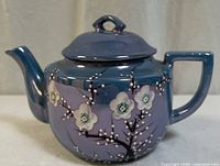 Front view of blue lustreware porcelain teapot showing cherry blossom design