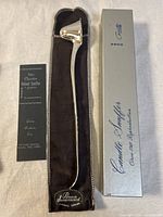 Snuffer displayed in velvet pouch next to sleeve box and information card