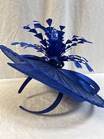 Side view of navy blue fascinator showing headband, round base, and decorative feather sprays