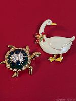 Front view of both duck and turtle brooches