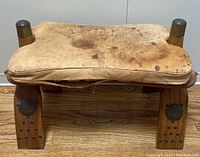 Full view wooden camel saddle stool with leather seat