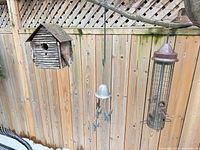 Wood birdhouse feeder, hanging rooster wind chime, metal tube feeder on fence