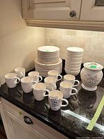 Overall lot: stacks of plates, bowls, mugs and lidded cookie jar on countertop